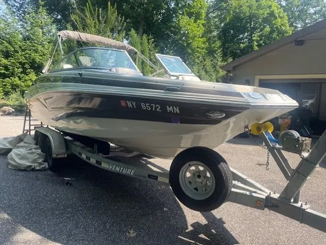 Slide: The Image of 2018 Crownline Eclipse E215 XS boat on trailer, parked outdoors near garage. - 2
