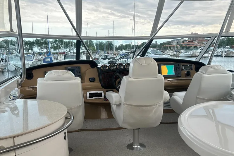 Slide: The Image of 2003 Carver 466 Motor Yacht interior with helm, white seating, and marina view. - 5