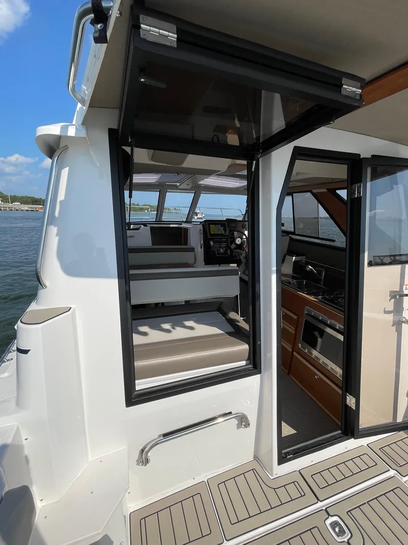 Slide: The Image of 2026 Cutwater C-288 Coupe interior view with open door, showcasing seating and kitchen area. - 12