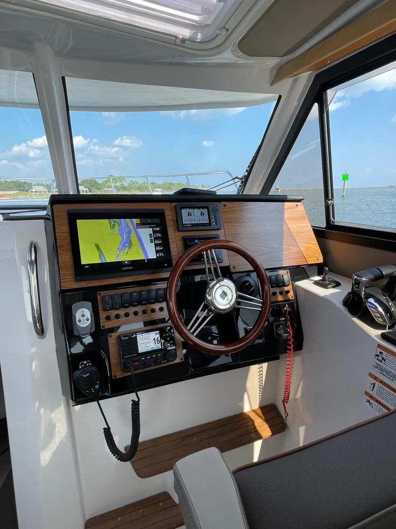 Slide: The Image of 2026 Cutwater C-288 Coupe helm with navigation screens and steering wheel, overlooking water. - 30