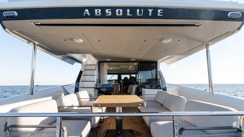 Slide: The Image of 2025 Absolute 60 Fly yacht, spacious deck with seating and table, ocean backdrop. - 16