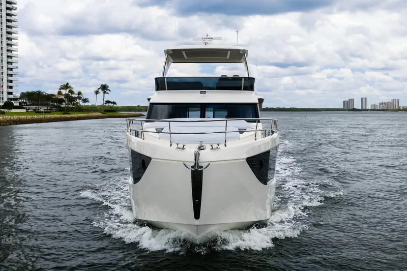 Slide: The Image of Front view of 2026 Absolute 60 Fly yacht cruising on a calm waterway. - 1