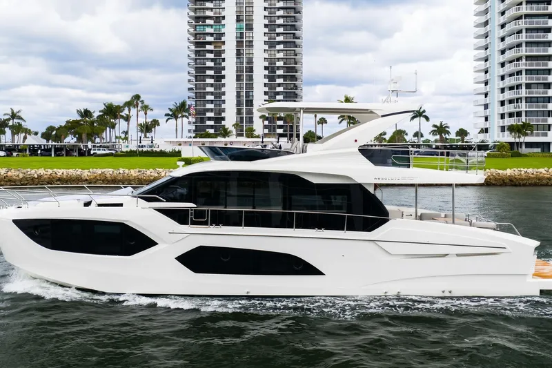 Slide: The Image of 2026 Absolute 60 Fly yacht cruising near modern waterfront buildings. - 2