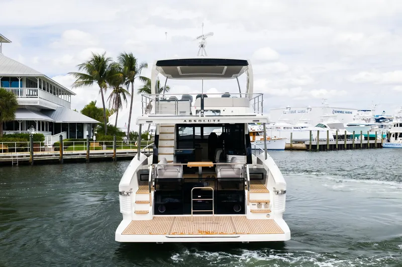 Slide: The Image of 2026 Absolute 60 Fly yacht docked near palm trees and waterfront homes. - 3