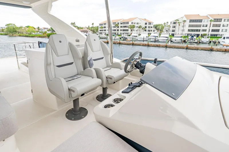 Slide: The Image of Luxury helm of 2026 Absolute 60 Fly yacht with dual seats and waterfront view. - 64