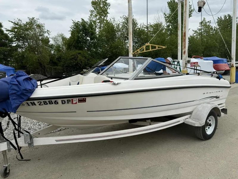 The Image of 2005 Bayliner 175 Bowrider on trailer, parked outdoors with trees in background. - 1