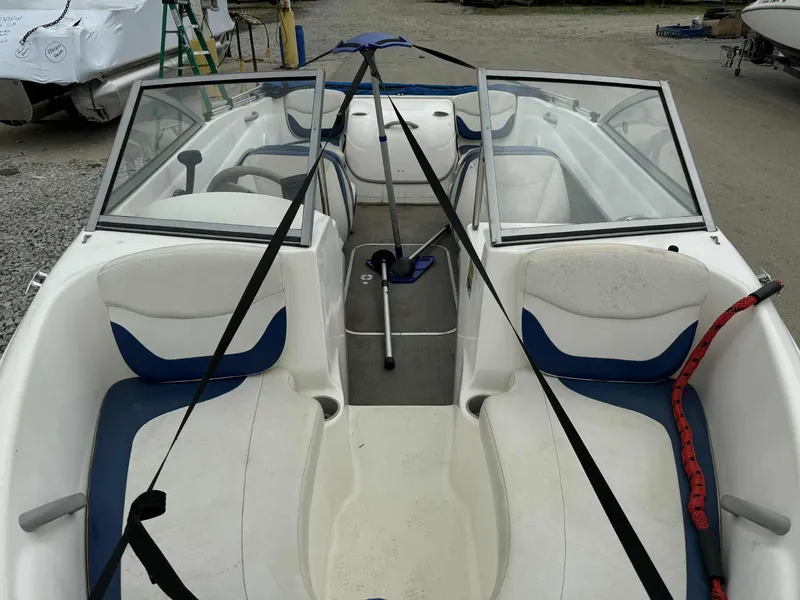 Slide: The Image of 2005 Bayliner 175 Bowrider interior with blue and white seating, parked on gravel. - 7