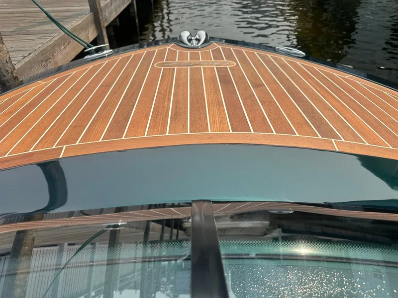 Slide: The Image of 2018 Chris-Craft Capri 21 boat with sleek wooden deck by the water. - 13