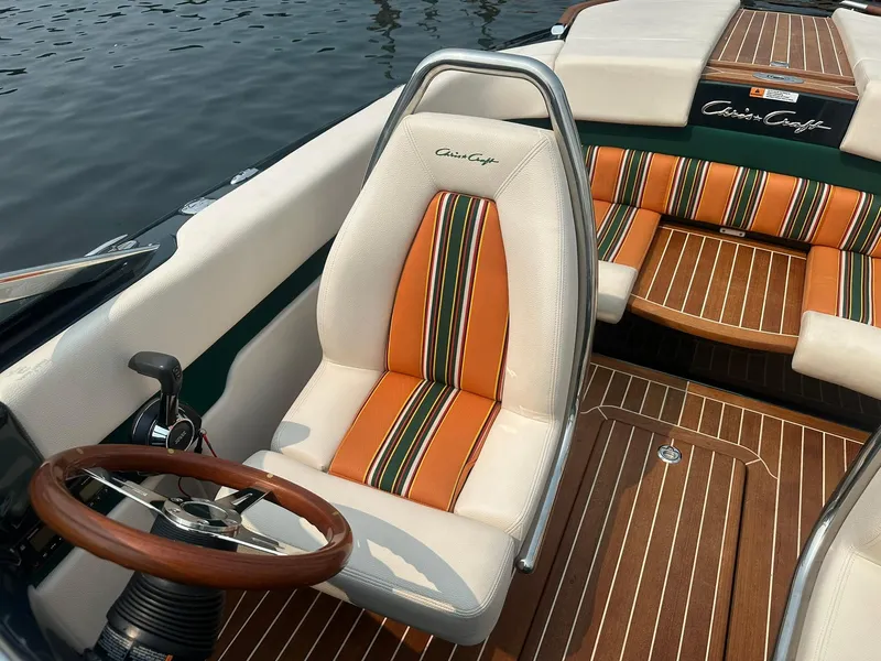 Slide: The Image of 2018 Chris-Craft Capri 21 boat interior with striped seats and wooden steering wheel. - 15