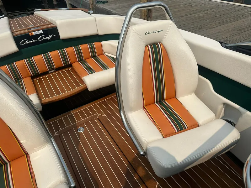 Slide: The Image of 2018 Chris-Craft Capri 21 interior with striped orange and green seating, wooden deck. - 16