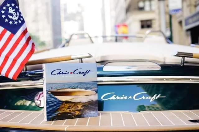 Slide: The Image of 2018 Chris-Craft Capri 21 boat with American flag and brochure on deck. - 21