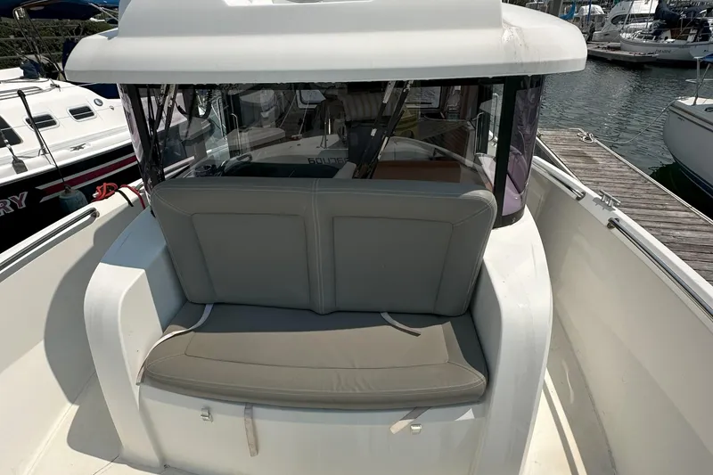 Slide: The Image of 2012 Beneteau Barracuda 9 Fly boat with cushioned seating at the helm, docked in a marina. - 10