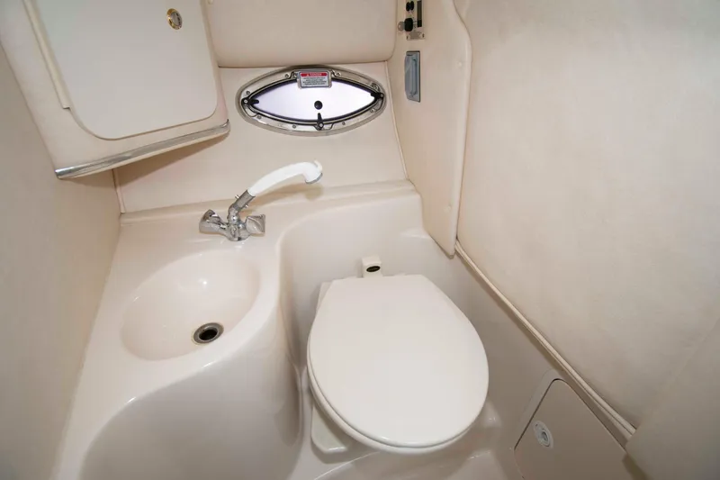 Slide: The Image of 2004 Sea Ray 290 Sun Sport boat bathroom with sink, toilet, and porthole window. - 15