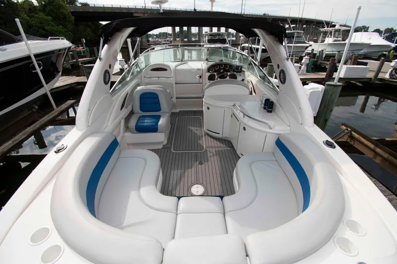 Slide: The Image of 2004 Sea Ray 290 Sun Sport boat interior with white and blue seating at a marina. - 4