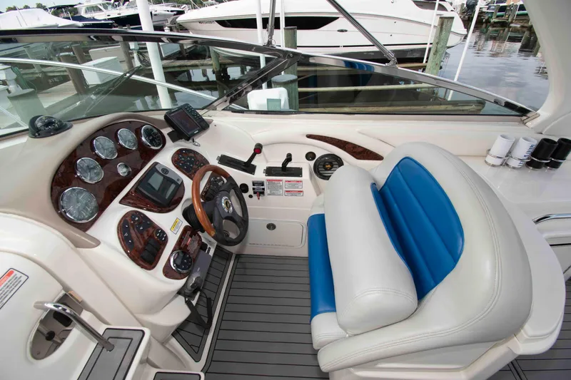 Slide: The Image of 2004 Sea Ray 290 Sun Sport cockpit with steering wheel, gauges, and blue-accented seating. - 7