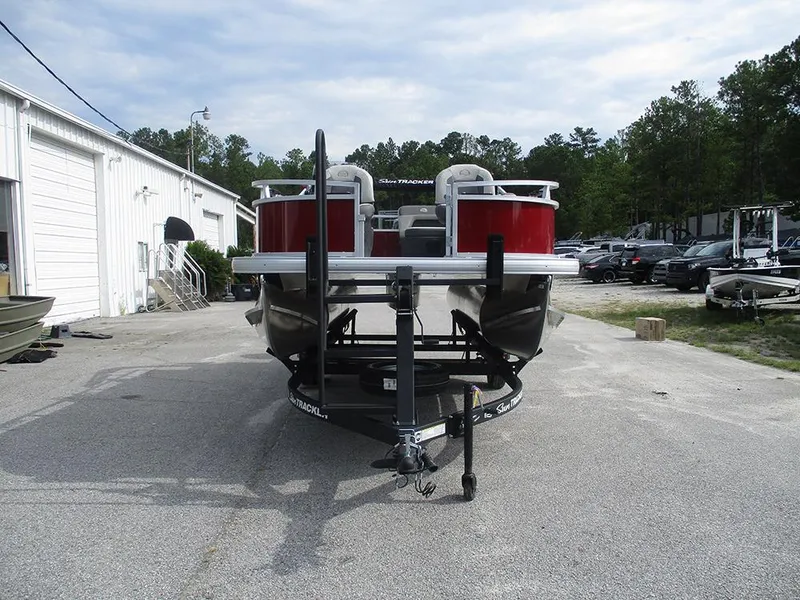 Slide: The Image of 2026 Sun Tracker Bass Buggy 16 XL Select pontoon boat on trailer, parked outdoors. - 4