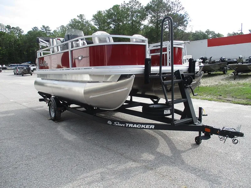 Slide: The Image of 2026 Sun Tracker Bass Buggy 16 XL Select pontoon boat on trailer in parking lot. - 6