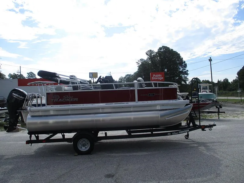 Slide: The Image of 2026 Sun Tracker Bass Buggy 16 XL Select pontoon boat on trailer, parked outdoors. - 7