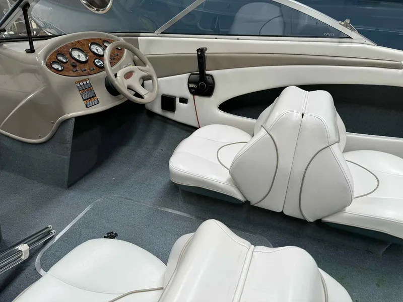 Slide: The Image of Interior of 2000 Bayliner 1750 Capri DX boat with white seating and dashboard controls. - 5