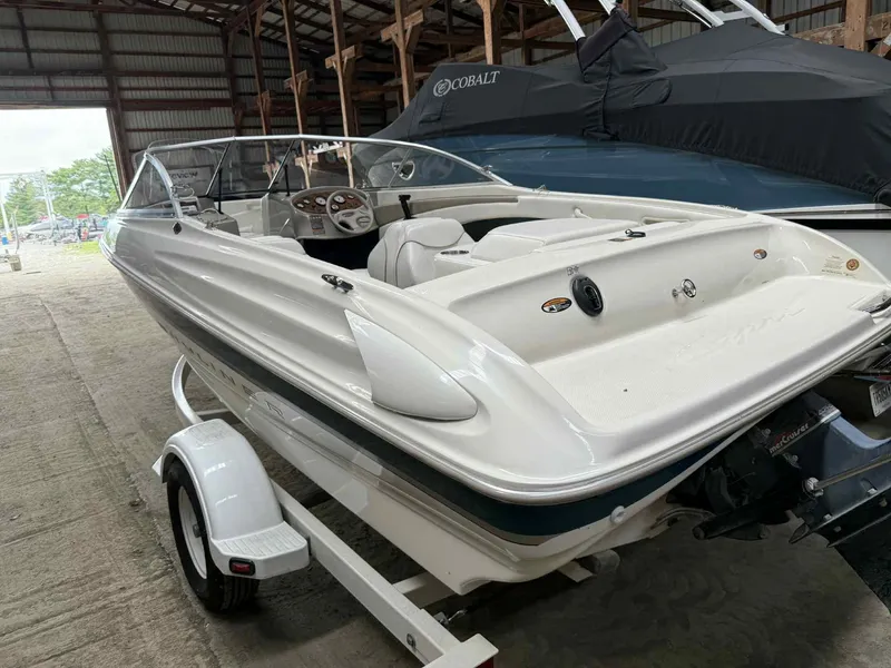 Slide: The Image of 2000 Bayliner 1750 Capri DX boat in storage, white exterior, on a trailer. - 8