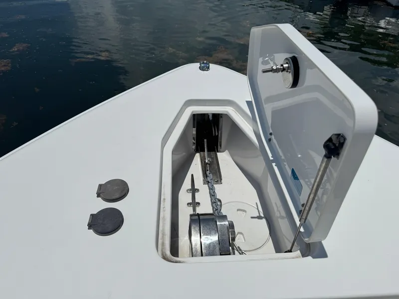 Slide: The Image of 2024 Sea Hunt Gamefish 27 anchor compartment with open hatch, showing chain and winch. - 29