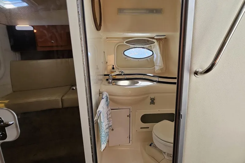 Slide: The Image of 2006 Rinker 300 Express Cruiser bathroom with sink, toilet, and porthole window. - 10