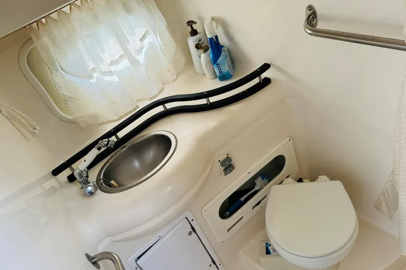 Slide: The Image of 2006 Rinker 300 Express Cruiser bathroom with sink, toilet, and cleaning supplies. - 11