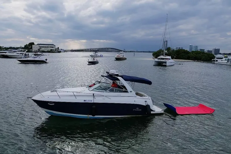 Slide: The Image of 2006 Rinker 300 Express Cruiser anchored in a scenic bay with other boats nearby. - 15