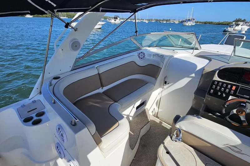 Slide: The Image of 2006 Rinker 300 Express Cruiser interior with seating and control panel, docked on a sunny day. - 4