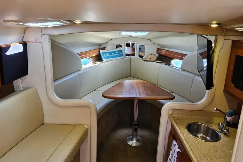 Slide: The Image of 2006 Rinker 300 Express Cruiser interior with seating, table, and kitchenette. - 7