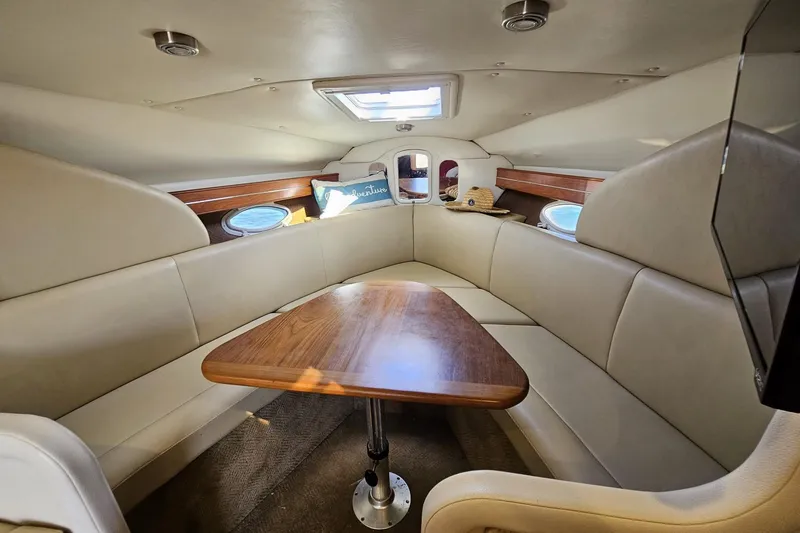 Slide: The Image of 2006 Rinker 300 Express Cruiser interior with beige seating and wooden table. - 8