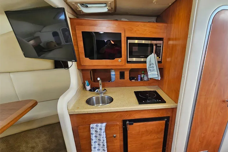 Slide: The Image of 2006 Rinker 300 Express Cruiser interior kitchen with sink, microwave, and TV. - 9