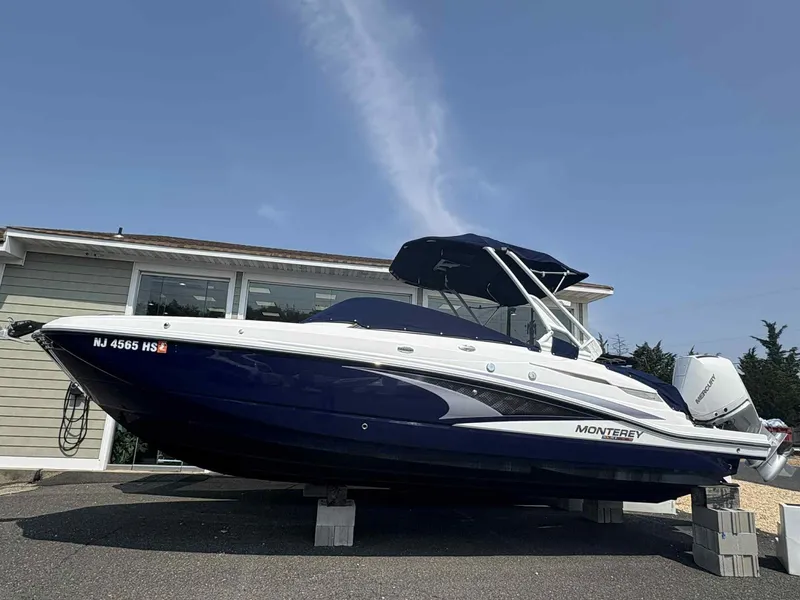 The Image of 2023 Monterey M65 boat on display, blue and white design, parked on blocks. - 1