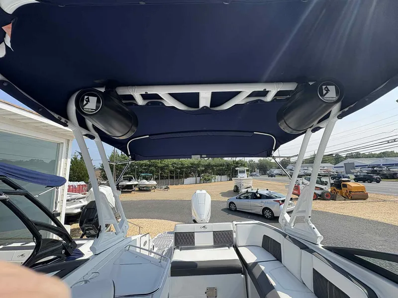 Slide: The Image of 2023 Monterey M65 boat interior with blue canopy and speakers, parked outdoors. - 5