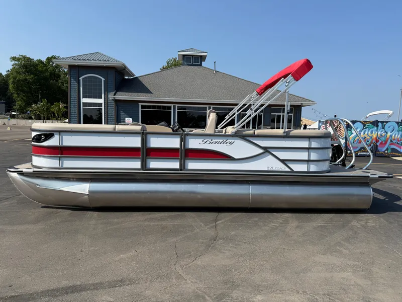 The Image of 2026 Bentley Pontoons Legacy 223 Navigator with red canopy, parked near a building. - 0