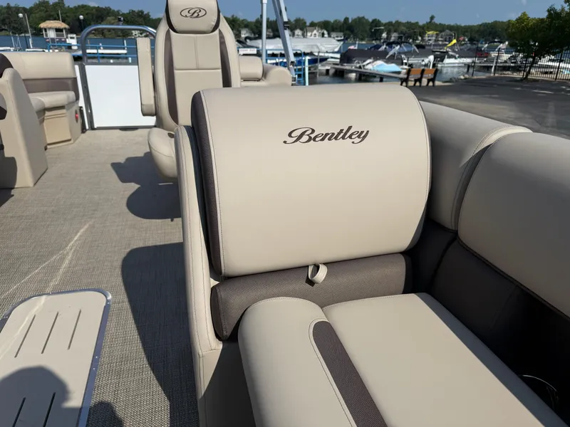 Slide: The Image of 2026 Bentley Pontoons Legacy 223 Navigator interior with beige seating at a marina. - 11