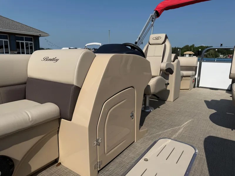 Slide: The Image of 2026 Bentley Pontoons Legacy 223 Navigator interior with beige seating and steering console. - 12