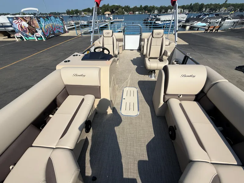 Slide: The Image of 2026 Bentley Pontoons Legacy 223 Navigator interior with beige seating at a marina. - 14