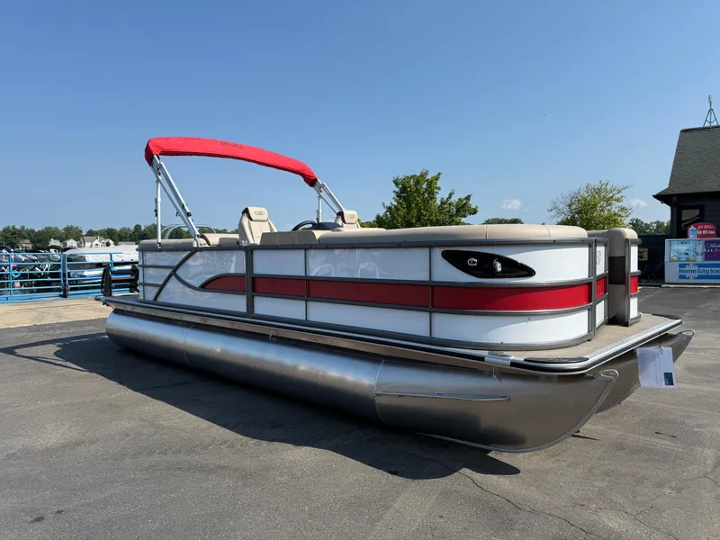 Slide: The Image of 2026 Bentley Pontoons Legacy 223 Navigator with red canopy, parked on pavement. - 2