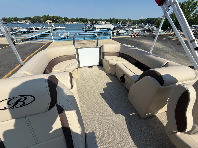 Slide: The Image of 2026 Bentley Pontoons Legacy 223 Navigator interior with beige seating at a marina. - 32