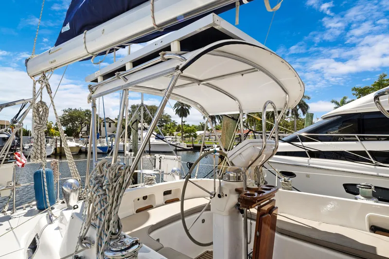Slide: The Image of 2004 Hylas 46 sailboat cockpit with steering wheel, docked in a marina under blue skies. - 11