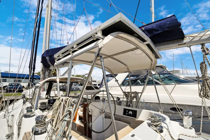 Slide: The Image of 2004 Hylas 46 sailboat cockpit with ropes and canopy, docked under blue sky. - 18