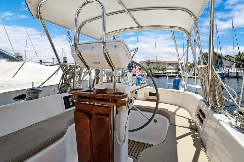Slide: The Image of 2004 Hylas 46 sailboat cockpit with steering wheel, marina view, and clear blue sky. - 21
