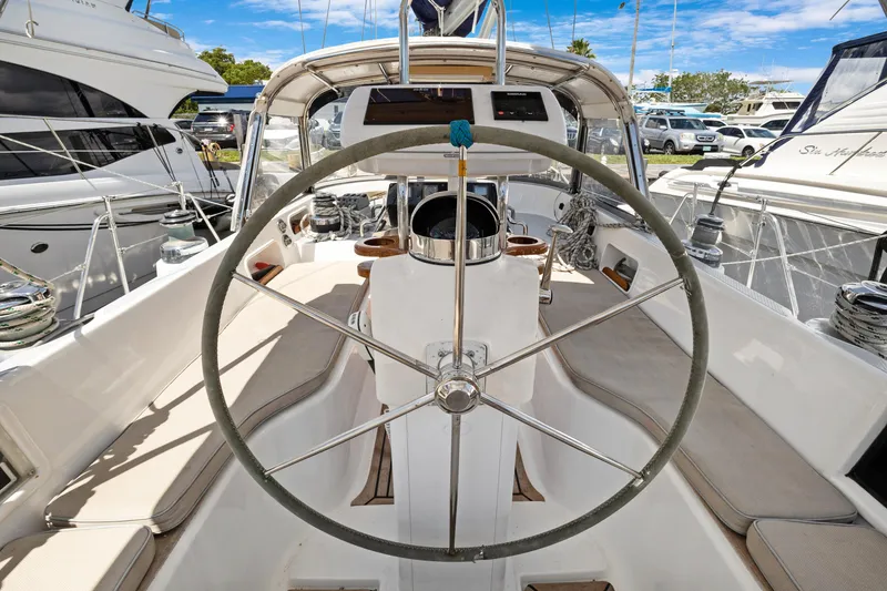 Slide: The Image of 2004 Hylas 46 sailboat cockpit with steering wheel, docked among other boats. - 25