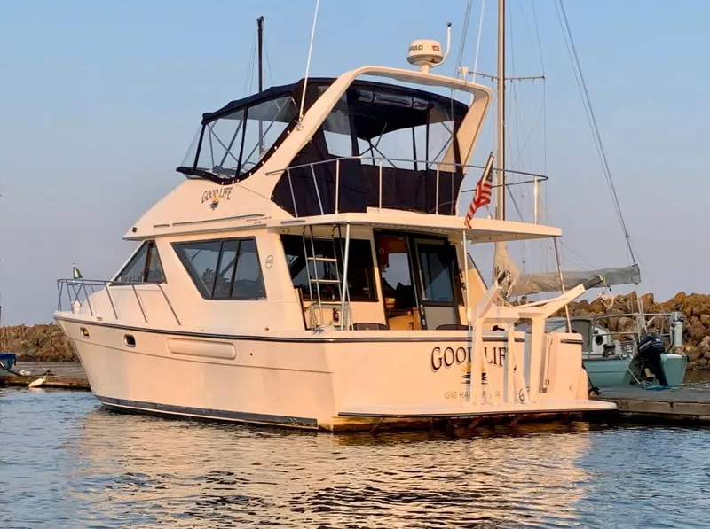 The Image of 2002 Bayliner 3988 yacht docked at sunset, featuring sleek design and spacious upper deck. - 0