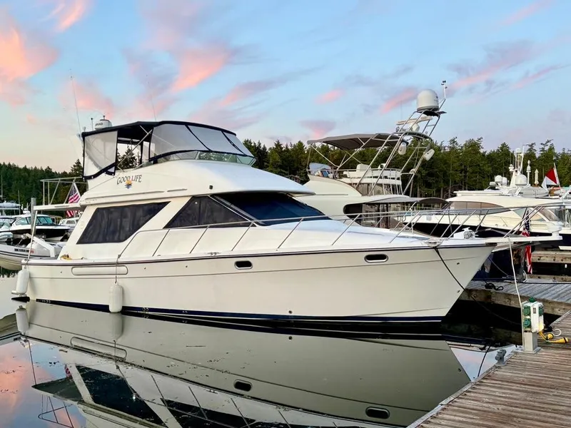 Slide: The Image of 2002 Bayliner 3988 yacht docked at marina, reflecting on calm water under a colorful sky. - 2