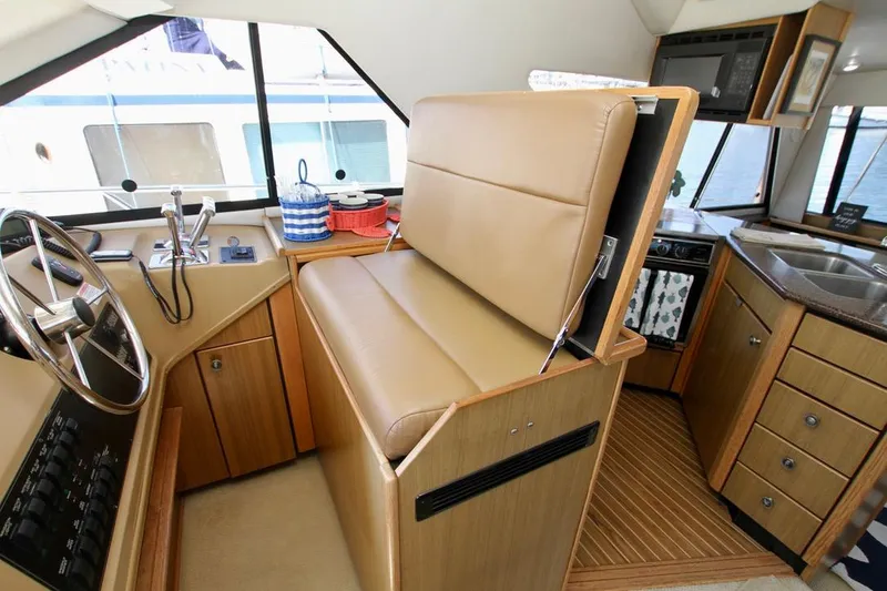 Slide: The Image of 2002 Bayliner 3988 yacht interior with helm, beige seating, and kitchen area. - 36