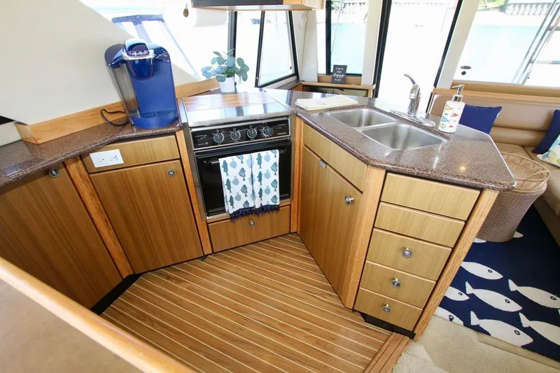 Slide: The Image of Bayliner 3988 2002 yacht kitchen with wooden cabinets, stove, and sink. - 45