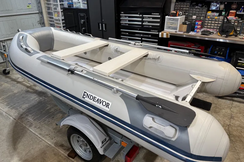 Slide: The Image of Inflatable boat "Endeavor" on trailer in garage, surrounded by tools and equipment. - 81