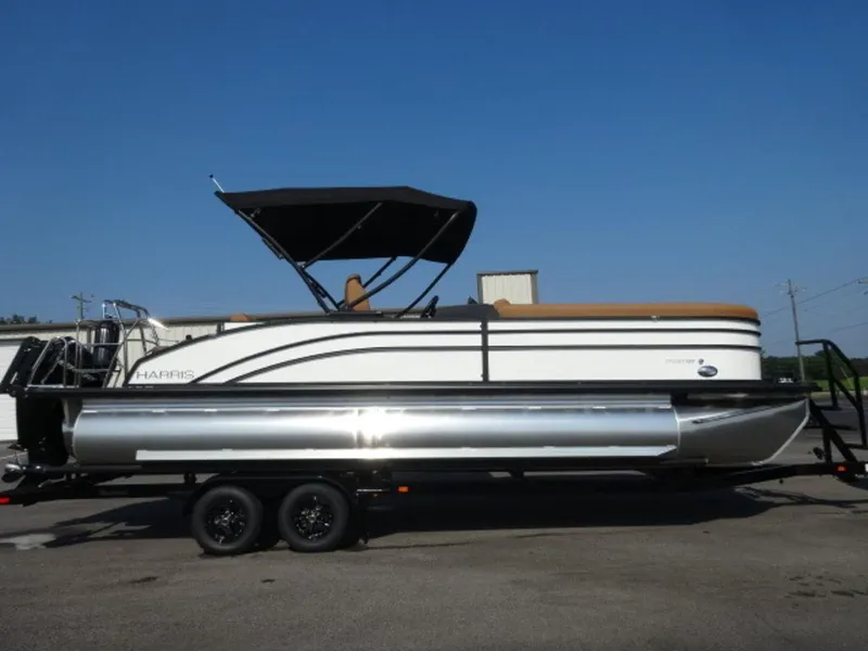 The Image of 2025 Harris Cruiser 250 LUX pontoon boat on trailer, under clear blue sky. - 1